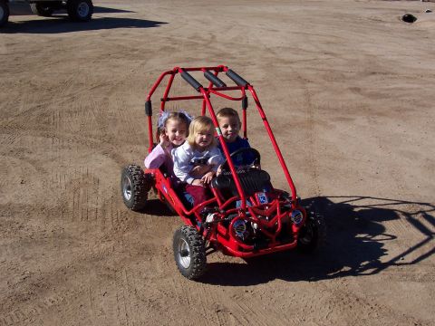 1981 Ford F-150 - Three children are riding in a red go-kart on a dirt surface. A watermark reads 'SUPERMOTORS.NET'.