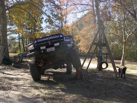 2001 Dodge 1500 - This lifted 2001 Dodge 1500 pickup truck is parked in a wooded area with a dog nearby.
