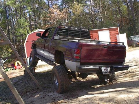 2001 Dodge 1500 - A maroon 2001 Dodge 1500 pickup truck is shown with large off-road tires, positioned on a dirt incline.