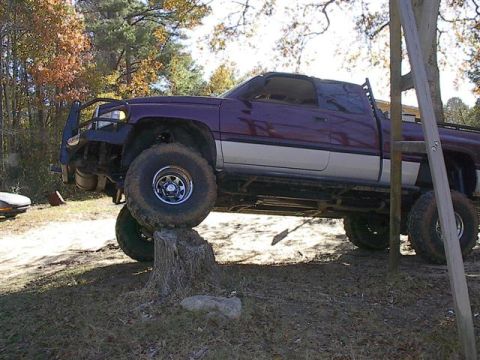 2001 Dodge 1500 - A modified pickup truck is positioned on a tree stump, its off-road capabilities.