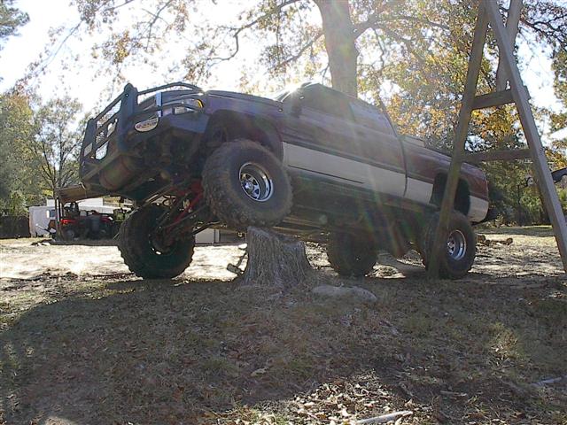 Lifted 2001 Dodge 1500 pickup truck on tree stump, 3q-front view