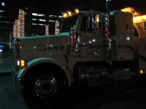 1968 Ford Mustang - A white tow truck is parked at night, illuminated by its own lights and nearby decorative lights.