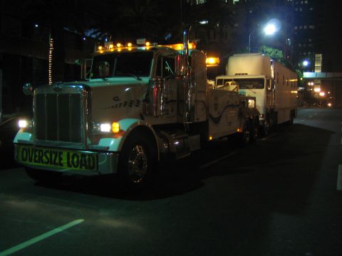 1968 Ford Mustang - A tow truck is parked at night, displaying an "OVERSIZE LOAD" sign on its front bumper.
