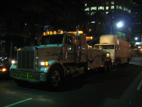 1968 Ford Mustang - A tow truck transports another truck at night on a city street.