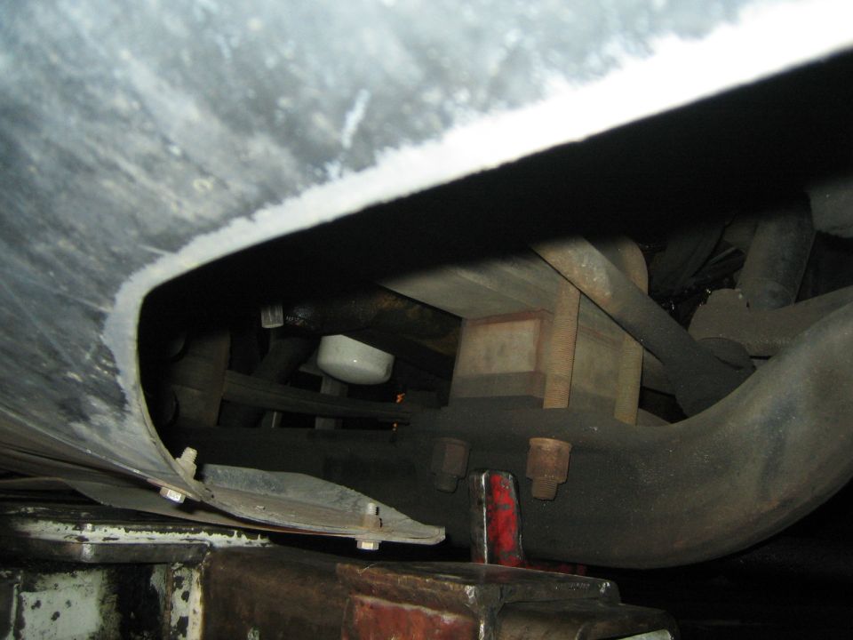Underside view of a vehicle, showing suspension components and a white oil filter