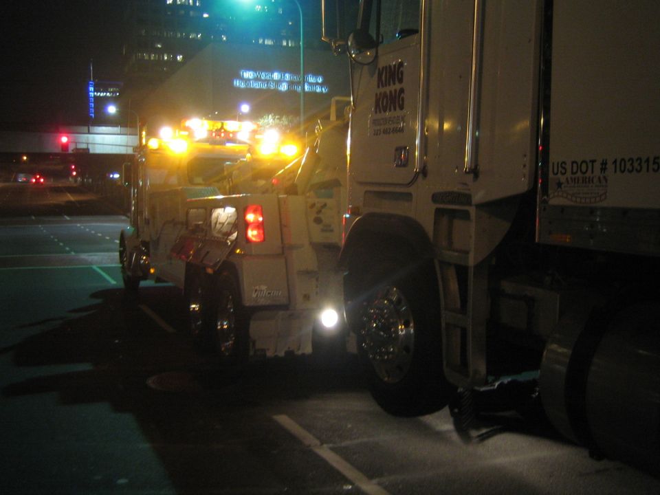 Tow truck with flashing lights next to a semi-trailer truck at night