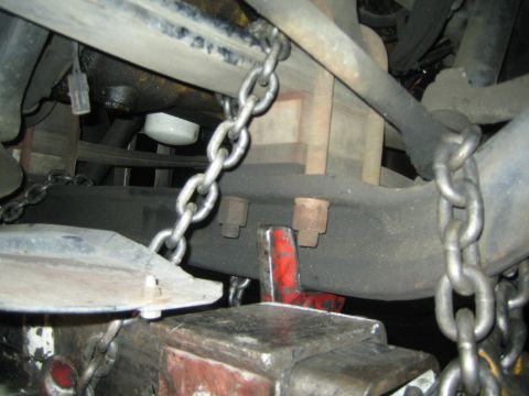 1968 Ford Mustang - Undercarriage of a vehicle secured with chains, with visible suspension parts and an oil filter.