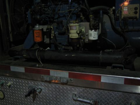 1968 Ford Mustang - Close-up view of engine and drivetrain components, including filters and hoses, mounted on a truck bed.