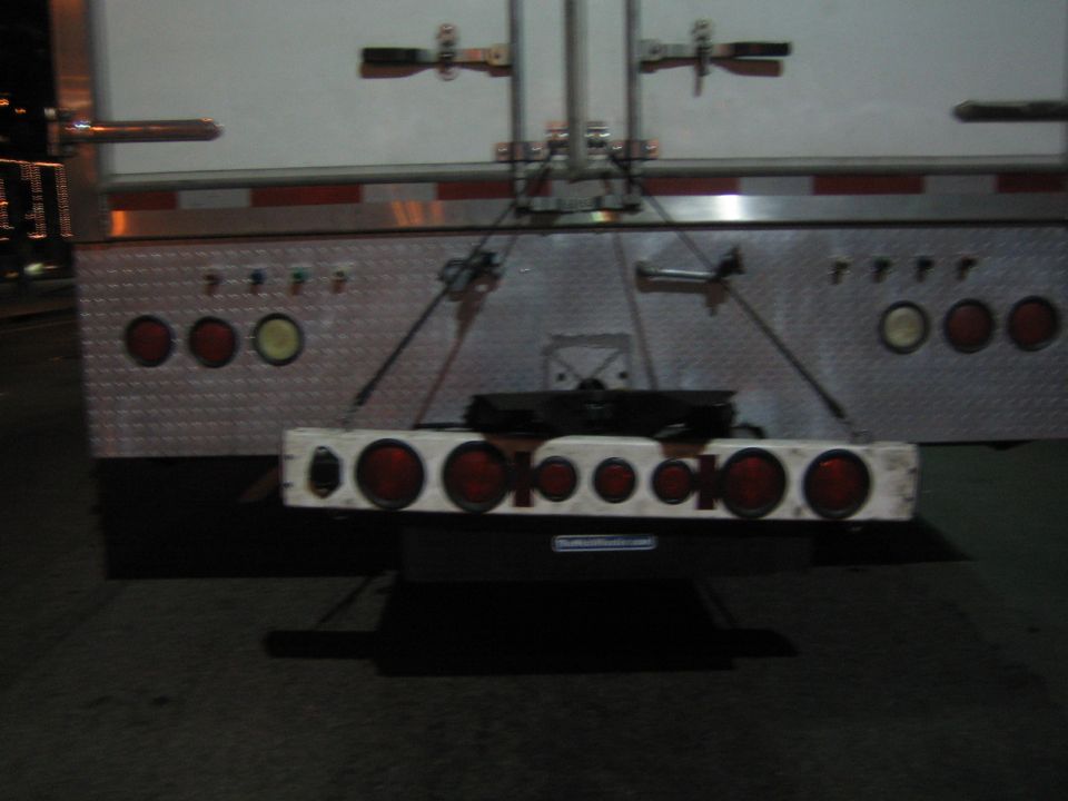 Back of a trailer with red taillights and diamond plate