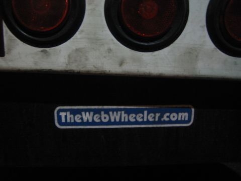 1968 Ford Mustang - A sticker with a website address is affixed to a dark surface below a row of red tail lights.
