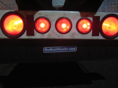 1968 Ford Mustang - The rear lights of a trailer are illuminated, with a website sticker visible below.