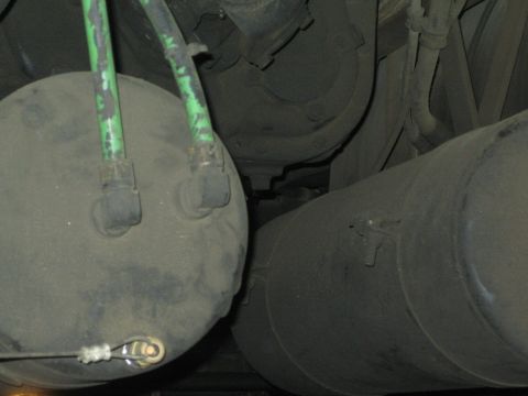 1968 Ford Mustang - The undercarriage of a truck is visible, two large, dusty air tanks and green hoses connected to them.