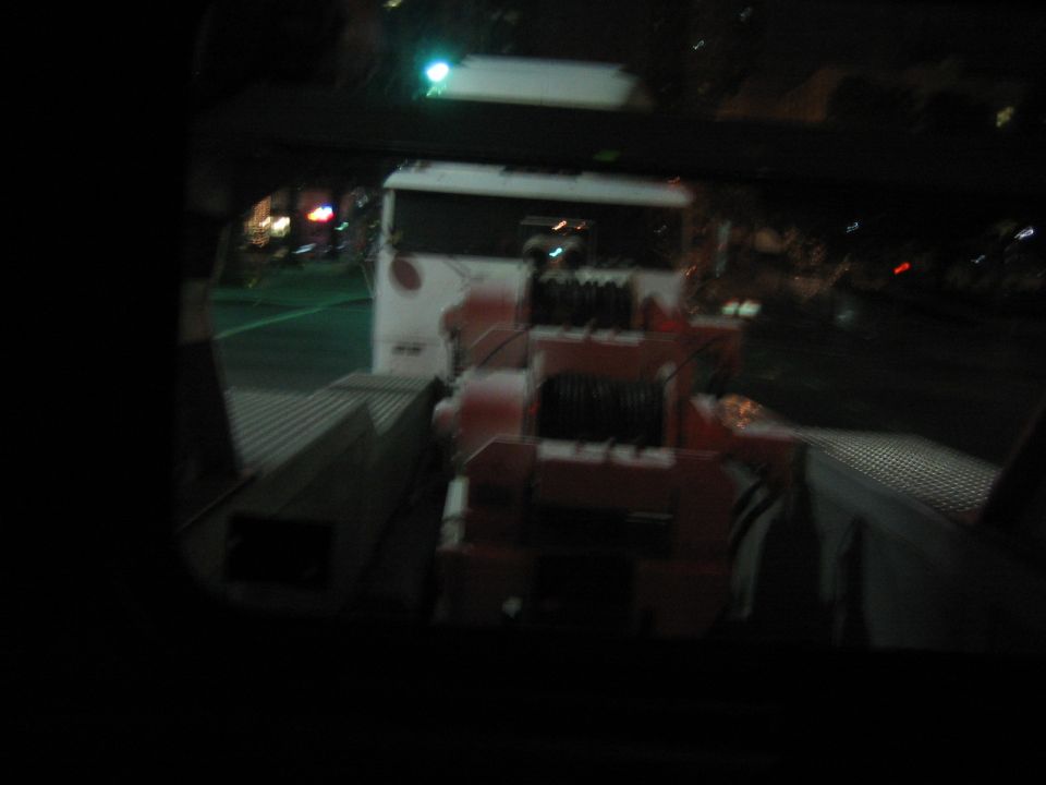 Tow truck with a large winch mechanism on the back, seen at night