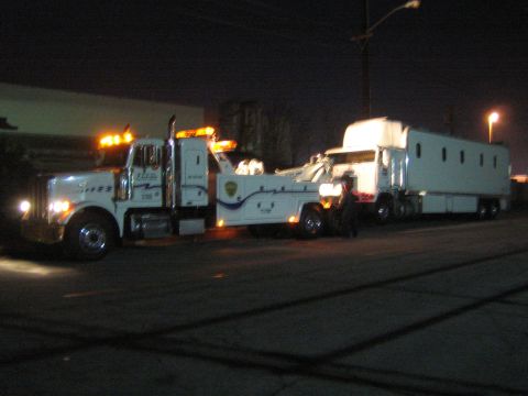 1968 Ford Mustang - A tow truck is seen at night, towing a large white trailer. The tow truck has 'PACE' written on its side.