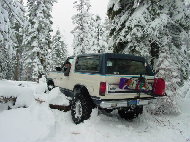 1986 Ford Bronco in snow with snowboards and gas can on rear rack