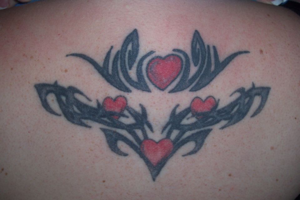 Tattoo of tribal designs and red hearts on skin