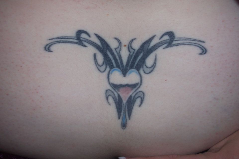 Tattoo of a stylized heart with tribal designs on skin