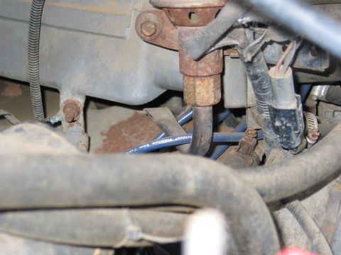 1989 Ford F-150 - Detail shot of engine components, including a fuel line and spark plug wire, showing signs of wear and rust.