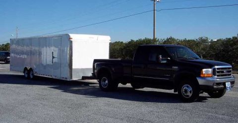 2000 Ford F-250 - A black 2000 Ford F-250 pickup truck is seen towing a large white enclosed trailer.