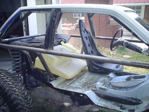 1981 Ford F-150 - Custom off-road buggy interior shows a roll cage, racing seat, and auxiliary fuel tank.