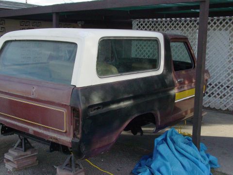 1979 Ford Bronco - Maroon 1978 Ford Bronco body with white hardtop, undergoing restoration and supported by jack stands.