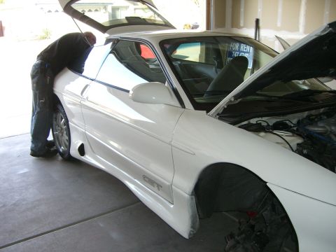 1996 Ford Probe - A person is working on a white sports coupe with its hood and trunk open in a garage.