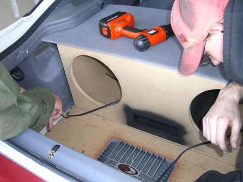 1996 Ford Probe - Installing a custom subwoofer box and amplifier in a car's trunk, with a drill and tools present.