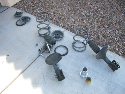 1996 Ford Probe - Car suspension components laid out, including struts, springs, and various hardware pieces.
