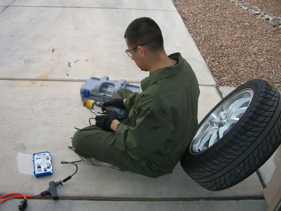 Person in green jumpsuit working on a tire with a rotary tool