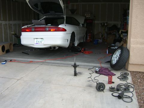 1996 Ford Probe - White coupe undergoing maintenance in a garage, with various suspension components laid out.