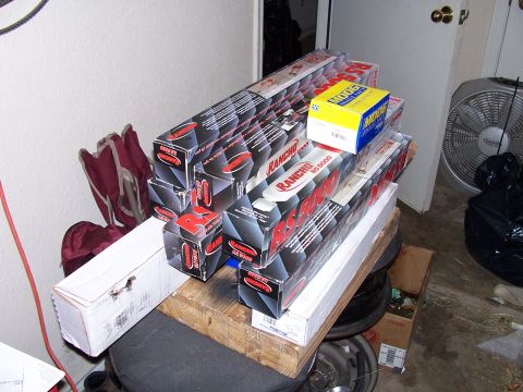 1982 Ford Bronco - Several boxes of Rancho RS5000 shocks and other automotive parts are stacked indoors.