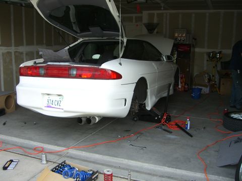 1996 Ford Probe - A white 1996 Ford Probe is being worked on in a garage, with its trunk and hood open.