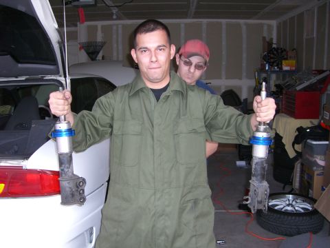 1996 Ford Probe - Two men in a garage with one holding car suspension parts.
