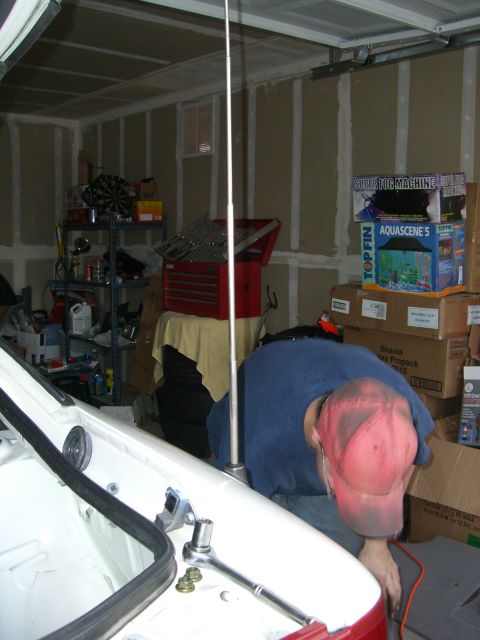 1996 Ford Probe - A person is working on the antenna of a car inside a garage, with various tools and storage boxes visible in the background.
