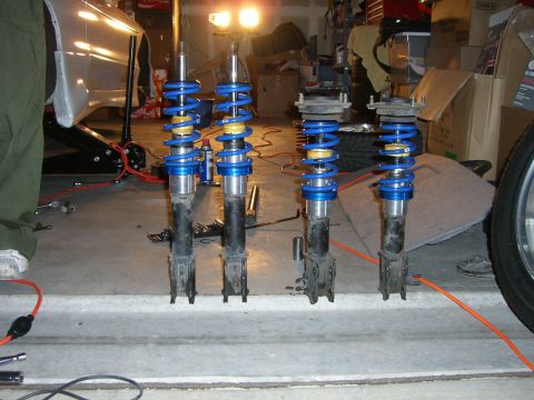 1996 Ford Probe - Four coilover suspension assemblies are shown in a garage, possibly for a car modification project.