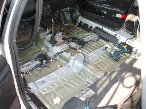 1993 Ford Taurus - The interior of a 1993 Ford Taurus is shown with its seats and carpet removed, revealing the floor pan and wiring.