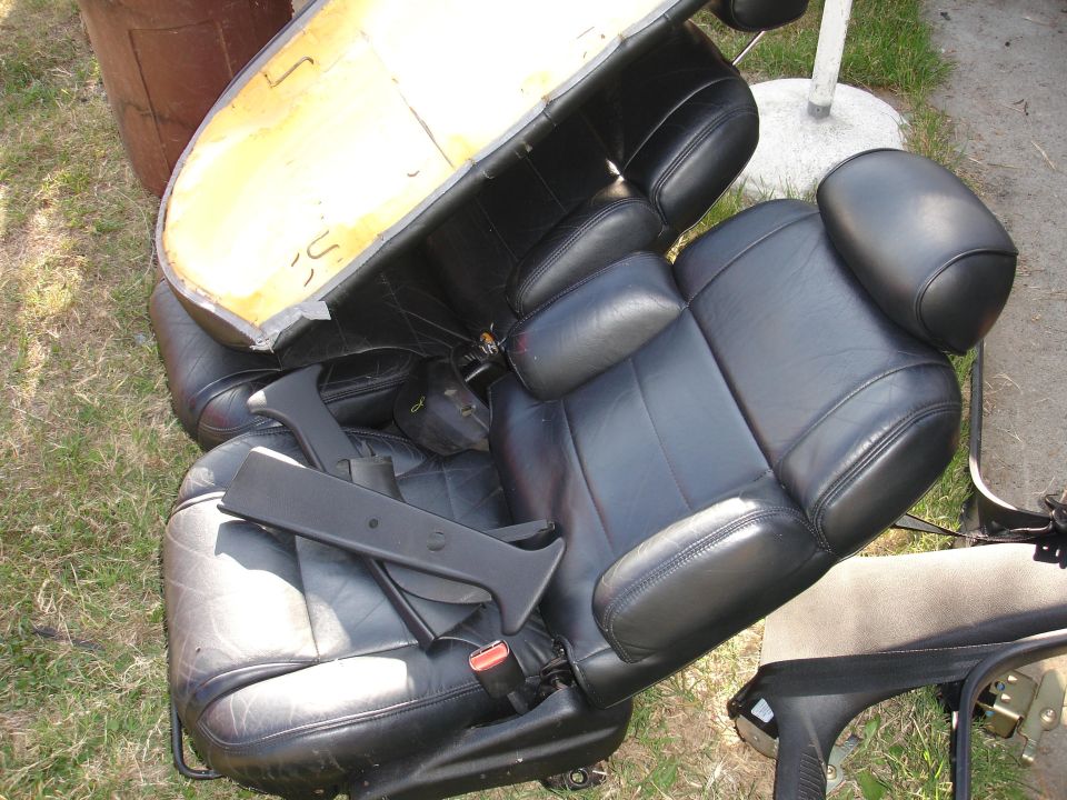 Black leather car seats with yellow foam backing visible