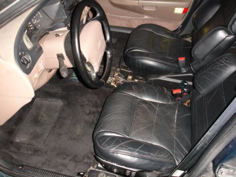 1993 Ford Taurus - The interior of a 1993 Ford Taurus shows black leather seats and a tan dashboard.
