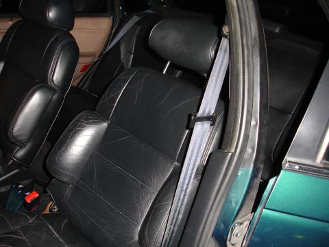 1993 Ford Taurus - Interior shot of car seats with black leather upholstery and seatbelts.