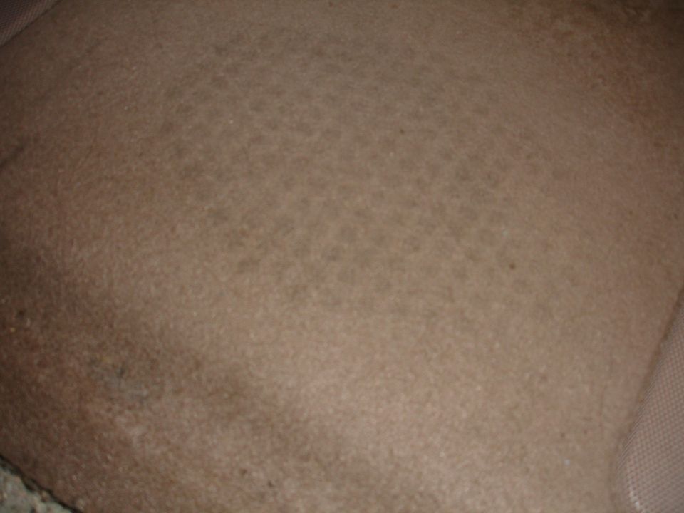 Tan car seat fabric with visible stains and wear