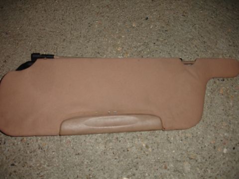 1993 Ford Taurus - A tan sun visor is shown lying on a concrete surface.