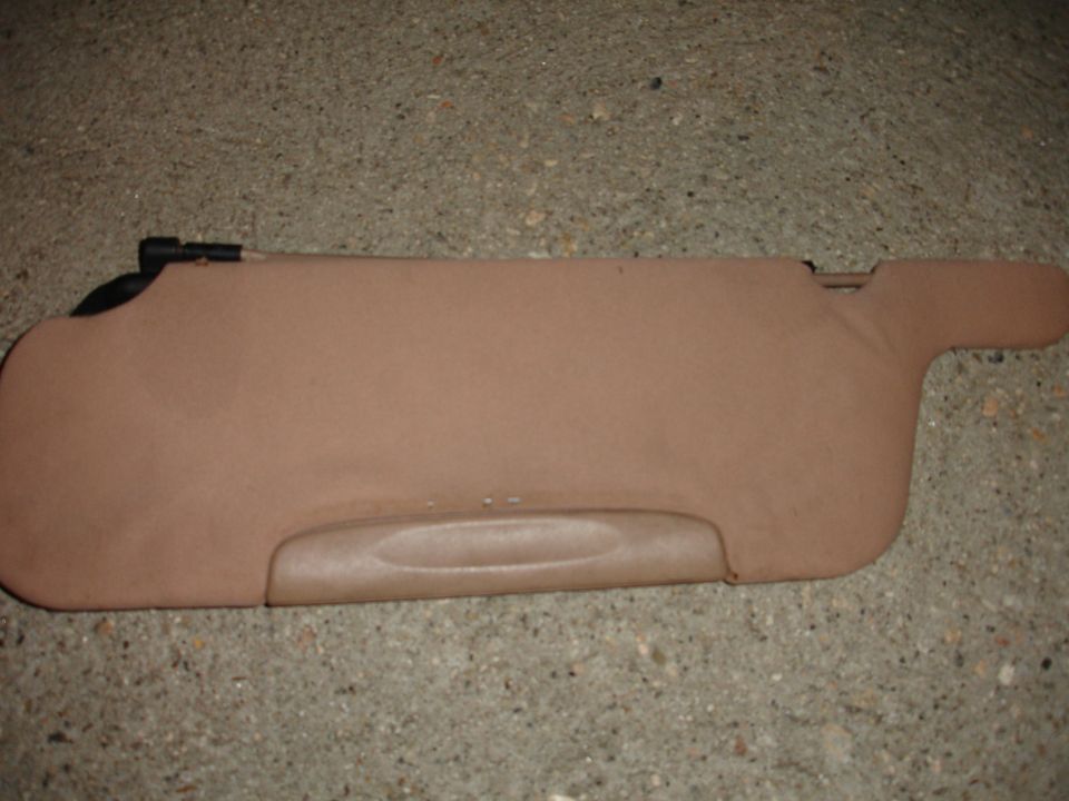 Tan car sun visor with a black clip on the left side