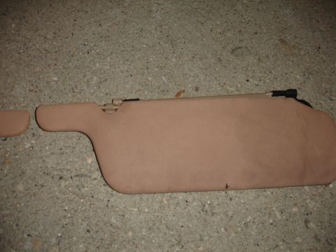 1993 Ford Taurus - A tan car sun visor is shown lying on a concrete surface.