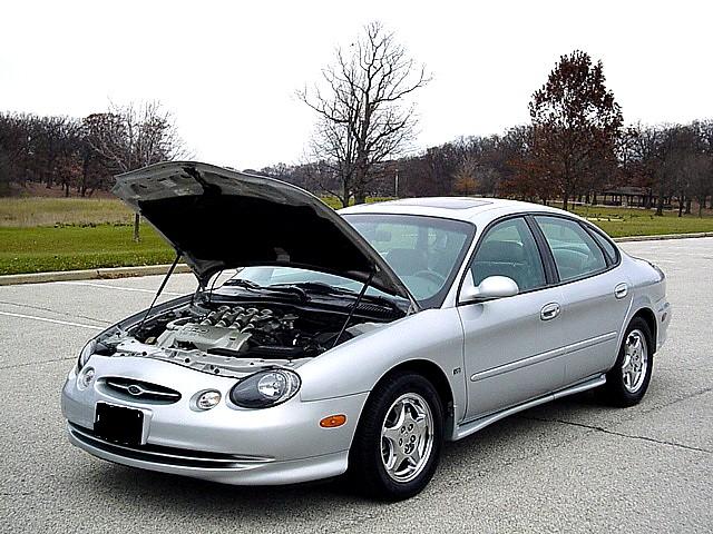 Silver 1998 Ford Taurus sedan with hood open, showing engine. Front 3/4 view