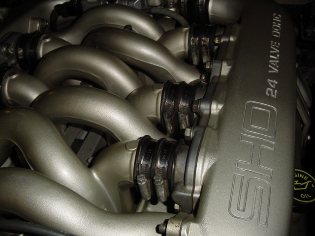 Close-up of a V-shaped engine intake manifold with 'SHO 24 VALVE DOHC' visible on one side