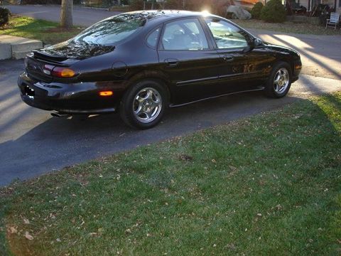 1998 Ford Taurus - Black 1998 Ford Taurus parked on a paved driveway next to a grassy lawn.