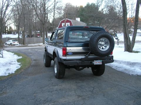 1994 Ford Bronco - A lifted Ford Bronco is parked in a driveway with snow on the ground and trees in the background.
