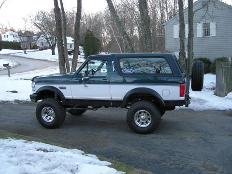 1994 Ford Bronco - A lifted 1992 Ford Bronco sits on a snowy driveway, its two-tone paint job visible.