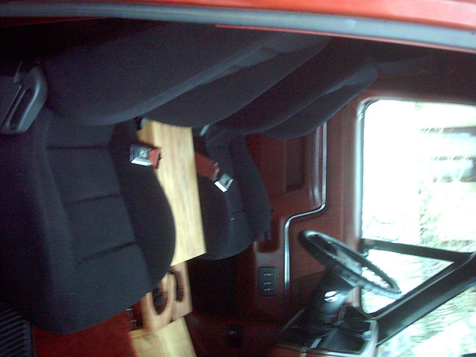 Vehicle interior showing black aftermarket seats and a wooden panel. Steering wheel visible
