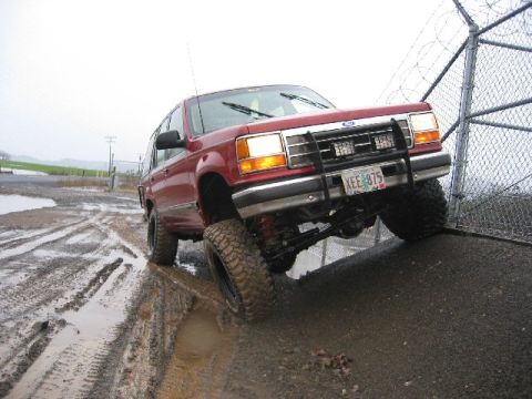 1991 Ford Explorer - 1991 Ford Explorer navigating a muddy terrain with a lifted suspension and off-road tires.